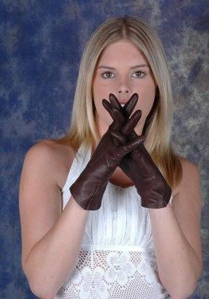 Blonde female pulls on brown leather gloves while wearing a white dress on leakfanatic.com