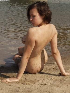 Amateur girl covers her naked body in sand while at a nude beach on leakfanatic.com