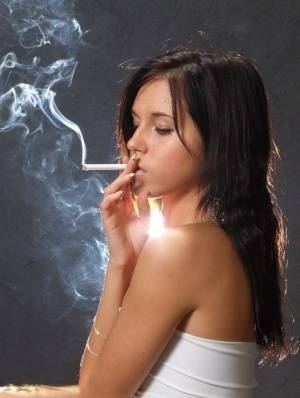 Young brunette smokes a cigarette while wrapped in tight white dress and heels on leakfanatic.com