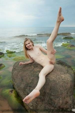 Slim teen Nimfa removes a black bikini to pose naked on seaside rocks on leakfanatic.com