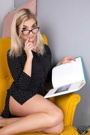 Geeky blonde Amelia undresses on a chair before playing with her shaved pussy on leakfanatic.com