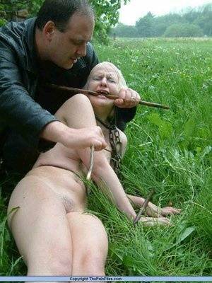 Naked blonde slave is caned and stomped on in a field of lush grass on leakfanatic.com