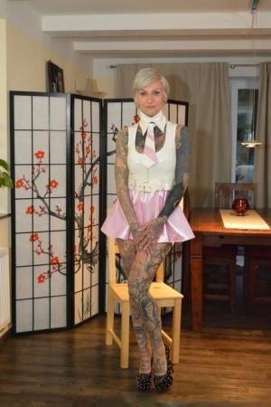 Tattooed platinum blonde Miss Francine models a raincoat over a latex dress on leakfanatic.com