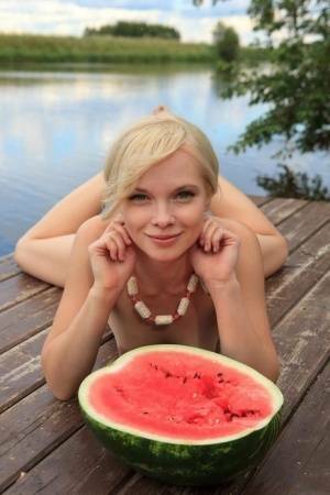 Beautiful blonde Feeona eats a watermelon while posing naked on lakeside dock on leakfanatic.com